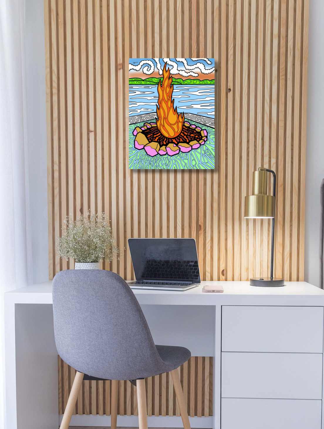 Colourful abstract painting of a campfire on a wall above a desk with a laptop.