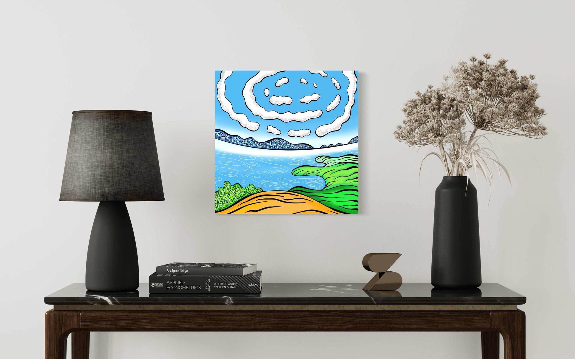 Table with a lamp, books, and a decorative item, featuring a colourful  contemporary landscape painting on the wall.