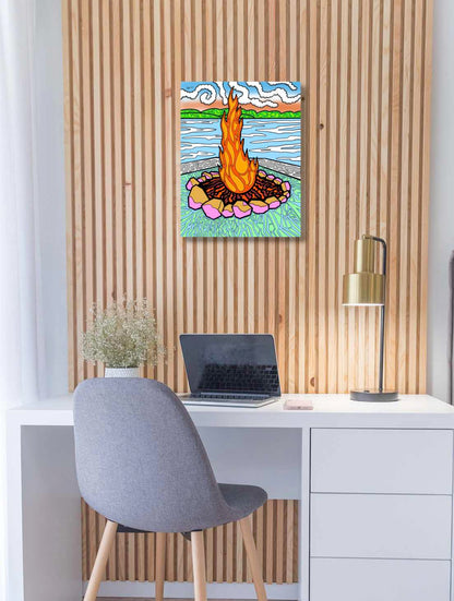 Colourful abstract painting of a campfire on a wall above a desk with a laptop.